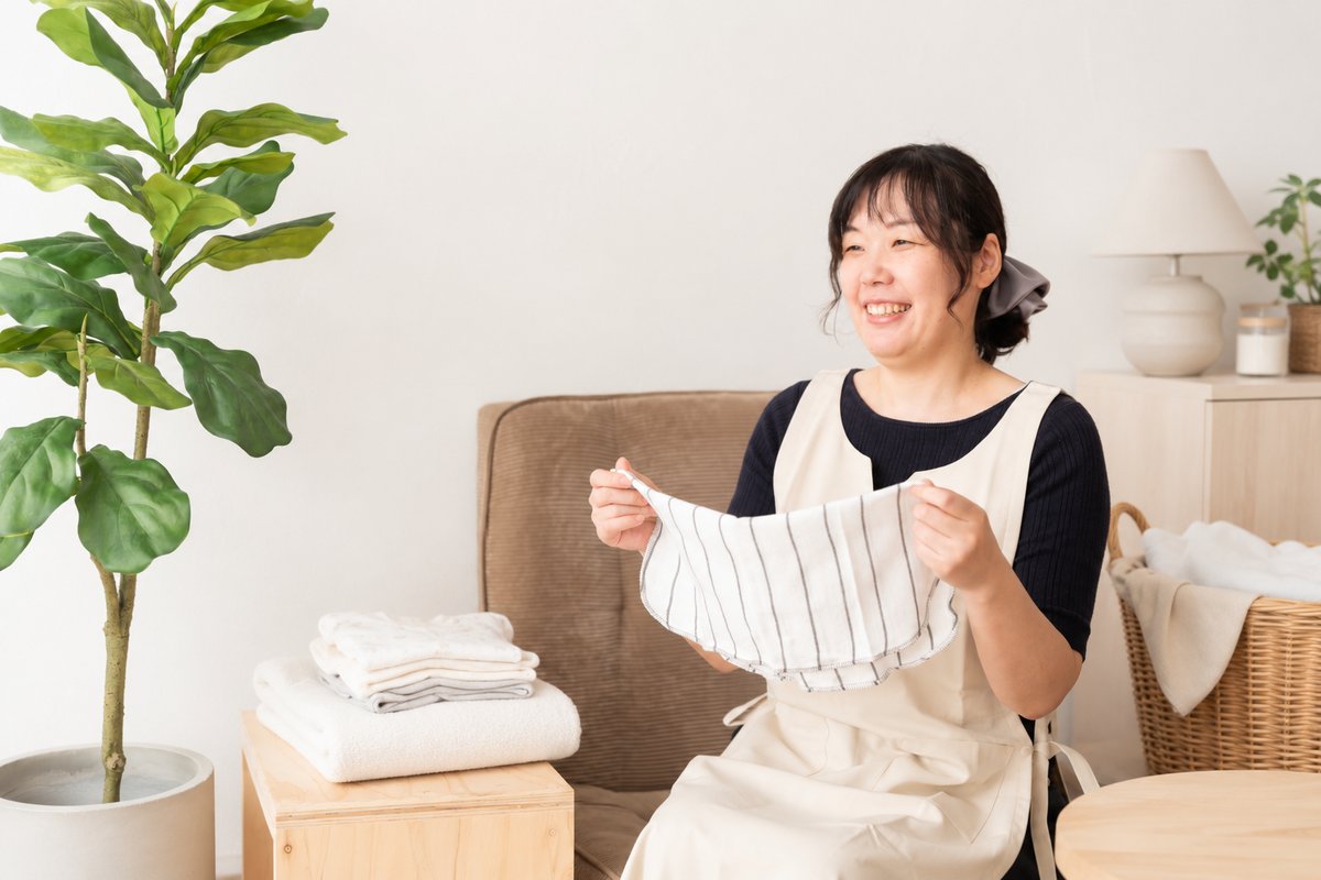 洗濯物をたたみながら笑顔で話す提供者